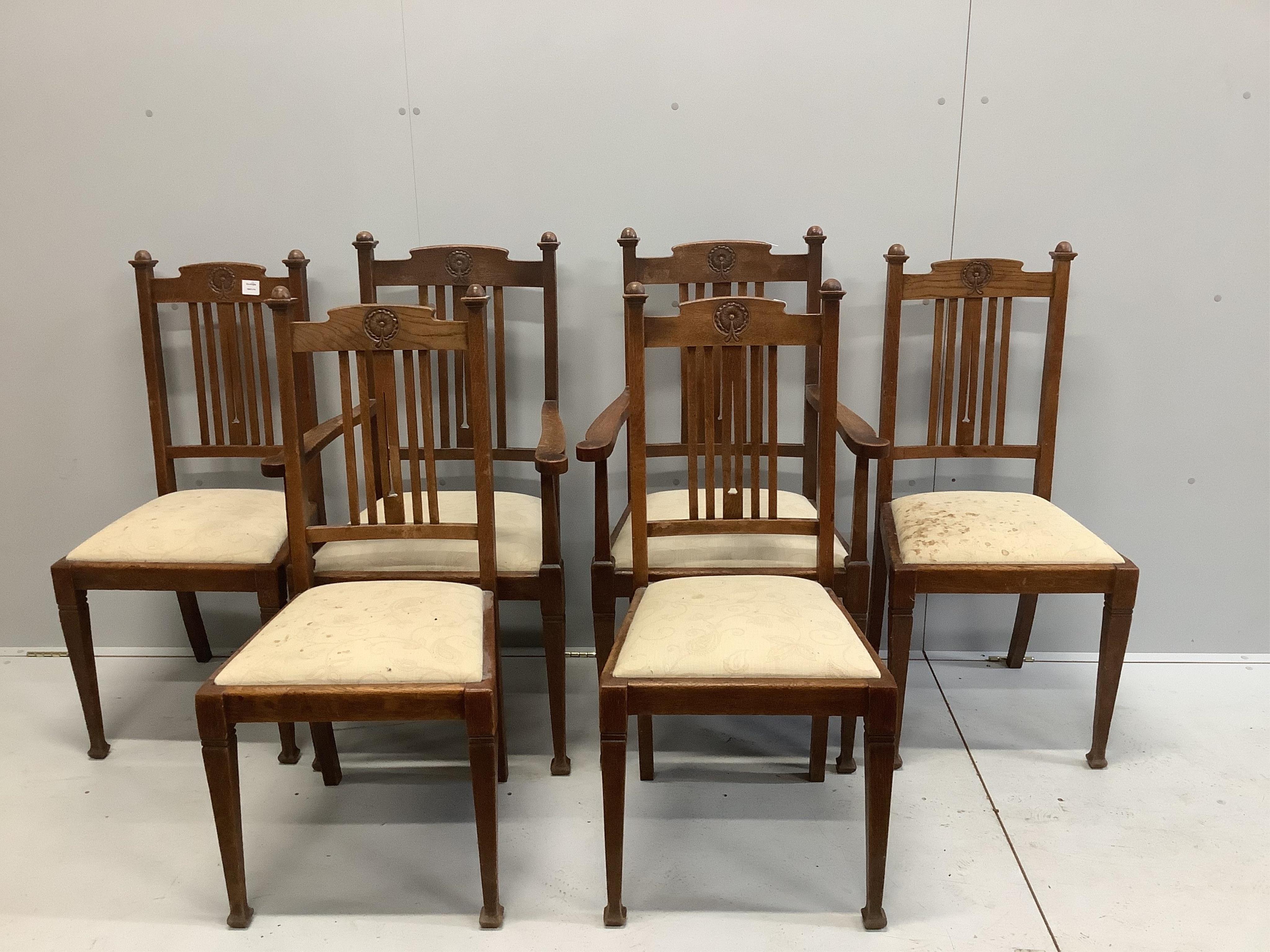 A set of six Arts & Crafts oak rail back dining chairs, with rosette carved crest rails, two with arms. Condition - fair